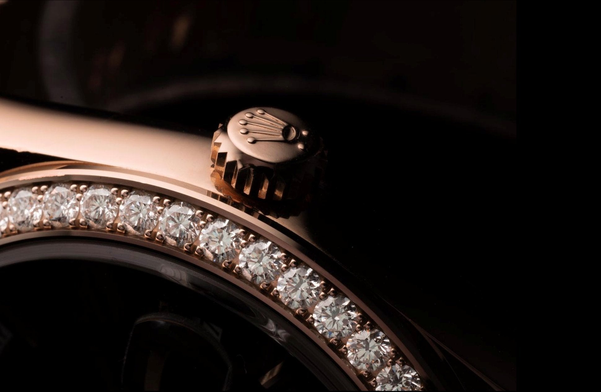 Close-up of a luxurious rose gold watch bezel adorned with sparkling diamonds. The focus is on the intricate crown and elegant watch face, conveying opulence.