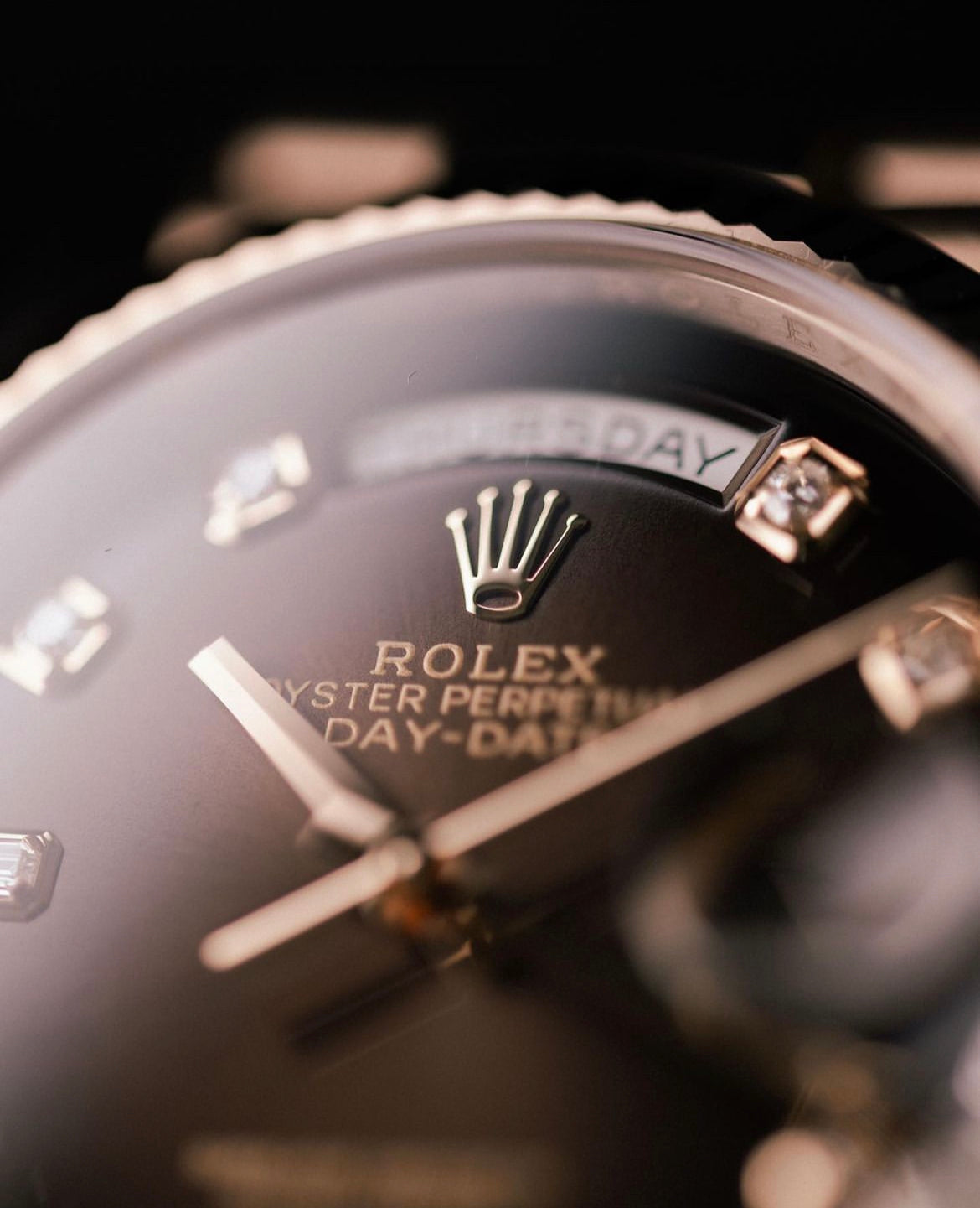 Close-up of a luxury watch face, featuring a gold emblem, diamond-like hour markers, and the words, "Oyster Perpetual Day-Date," conveying elegance.