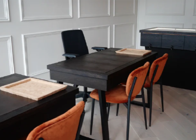 Modern reception space with dark wooden desks and orange cushioned chairs arranged neatly.