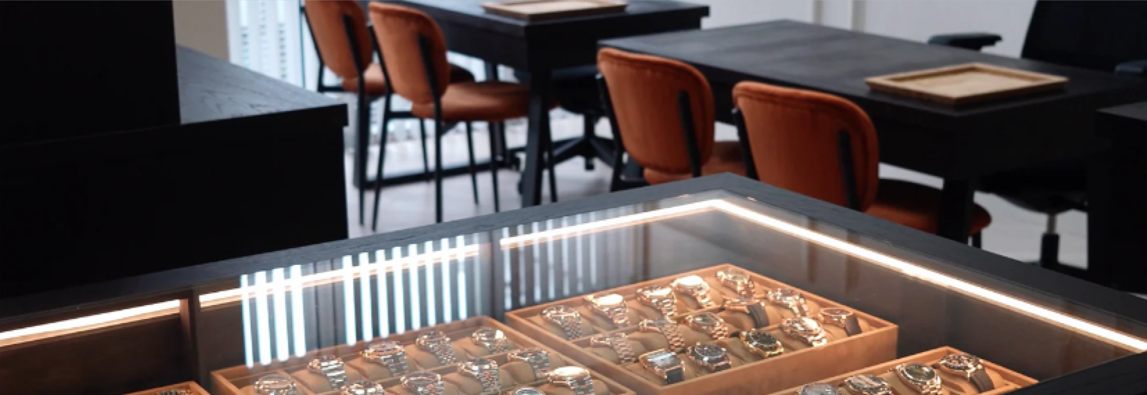 Close-up of a jewelry display case with various items, blurred interior in the background.