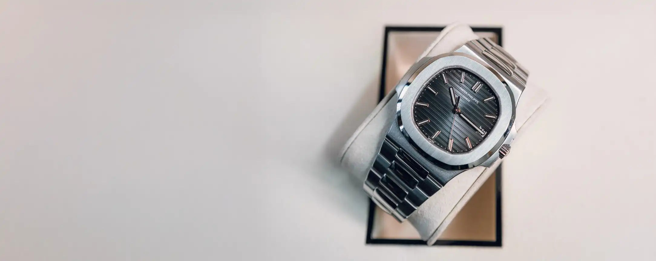 Luxury watch on a reflective surface with a light gray background